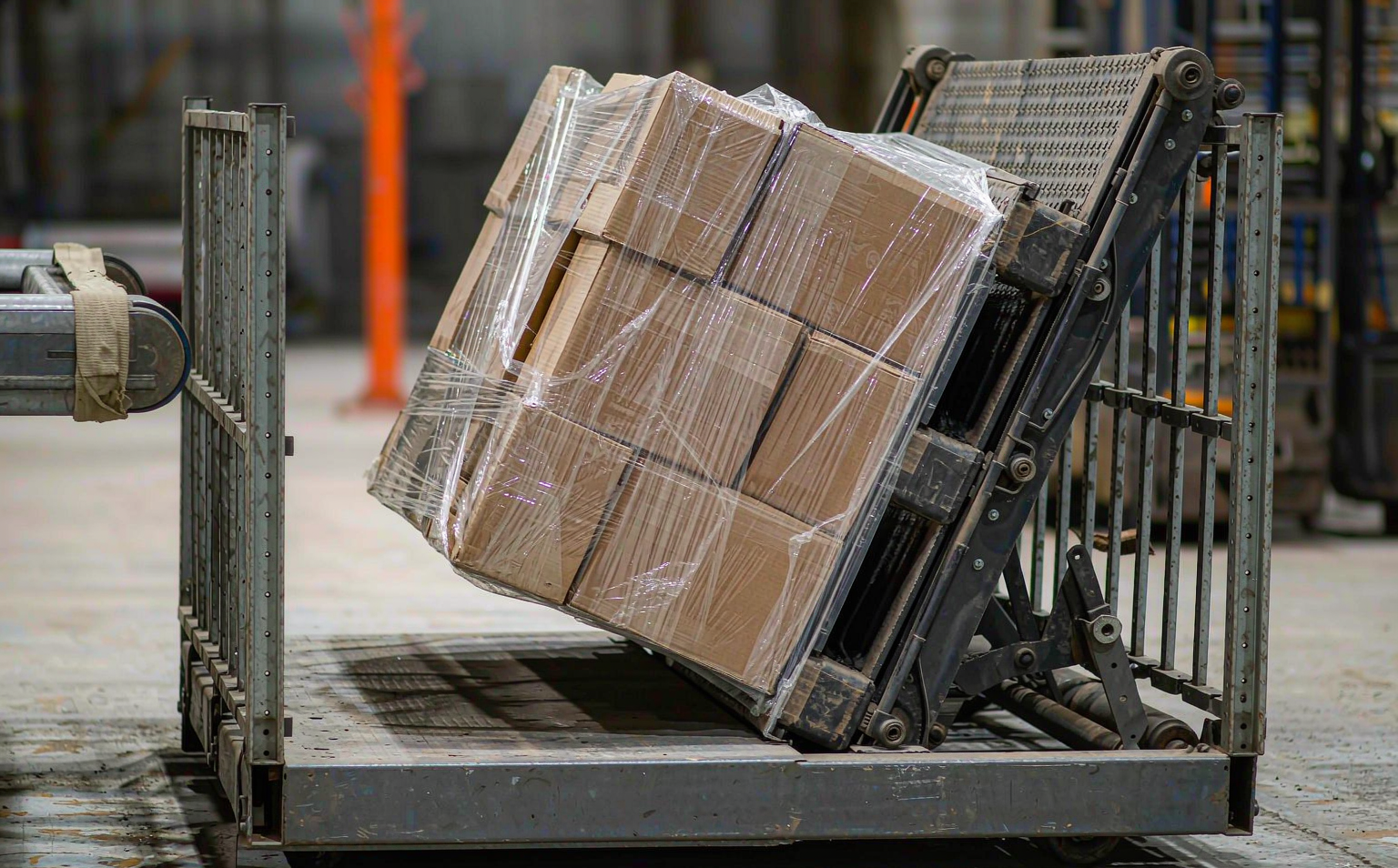 Automated stacker crane retrieving a stretch-wrapped pallet between towering high-bay storage racks