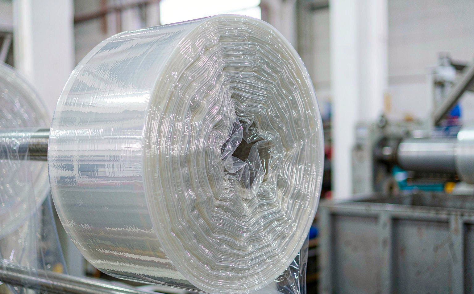 Close-up of a clear multi-layer machine stretch film roll showing its uniform, glossy cross-section on a warehouse wrapping line