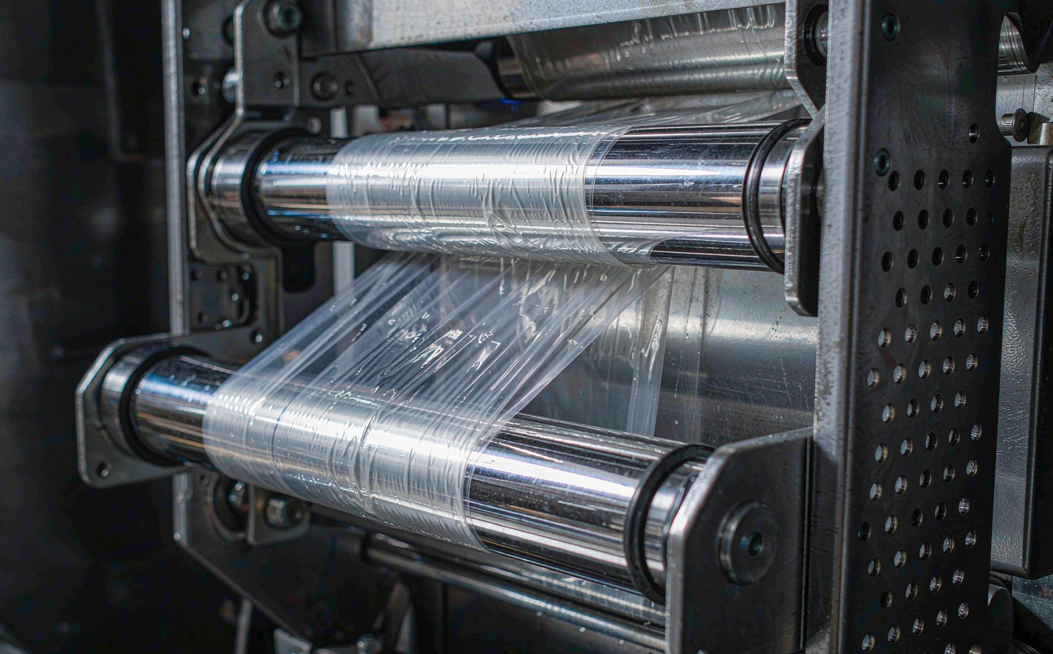 Close-up of power pre-stretch rollers elongating a web of transparent LLDPE machine stretch film