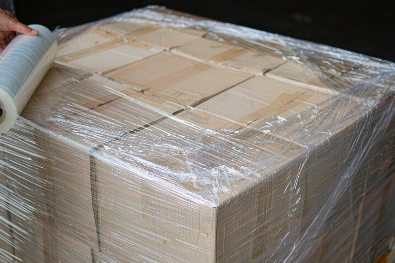 Close-up of hand stretch film being stretched and wrapped around the corner of a palletised carton load