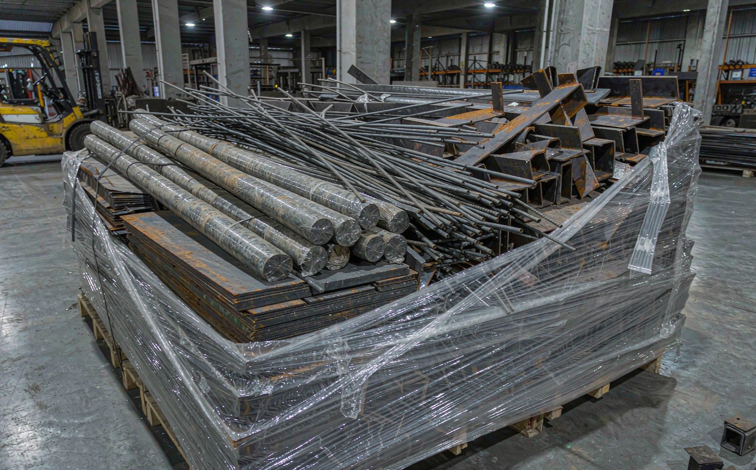 Stretch-wrapped pallet of metal stock with sharp-edged profiles in a steel service warehouse